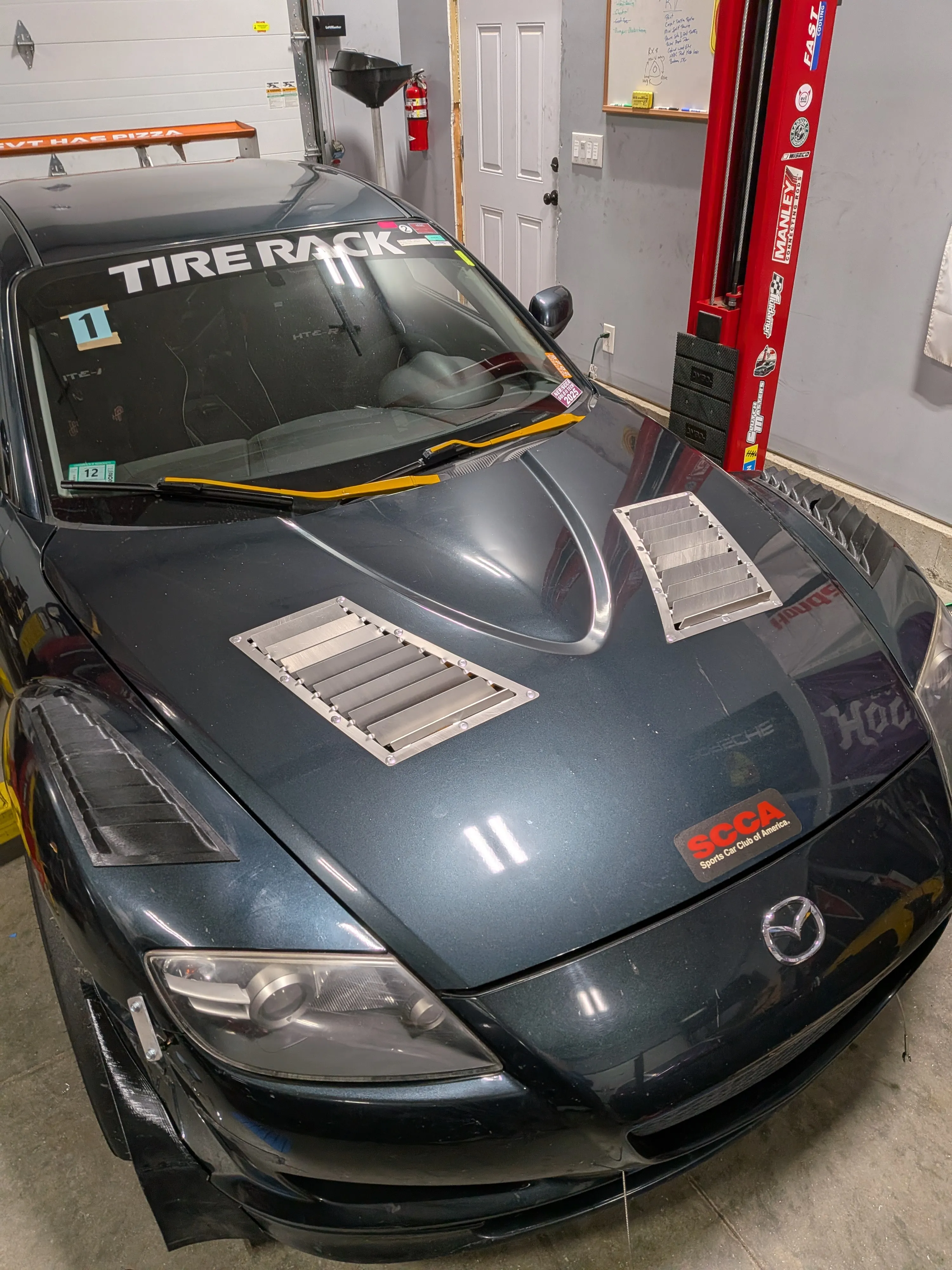 Grey RX8 with hood vents installed, parked in the shop