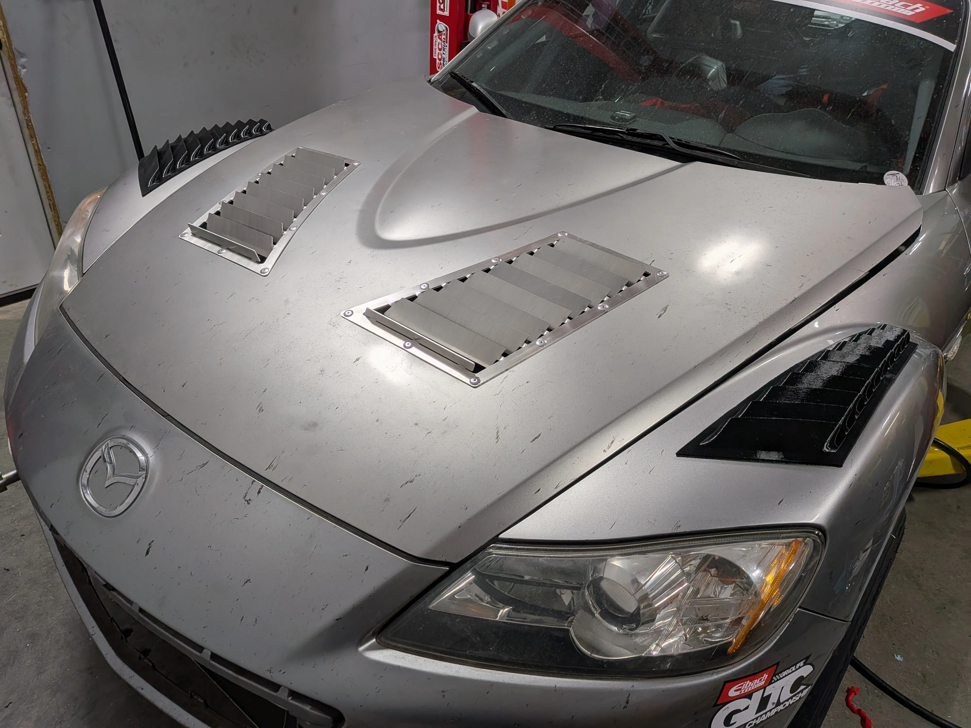 Aluminum hood vents installed on a grey Mazda RX8, front view